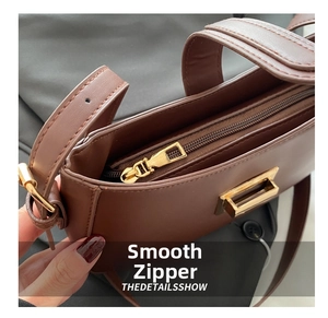 Detailed close-up of smooth gold zipper and premium brown leather texture on handbag