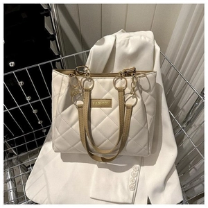 Close-up of beige quilted leather tote with gold metal rings and deep brown handles