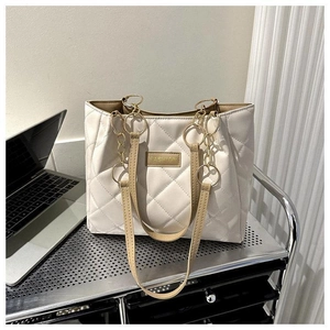 Detail of beige quilted tote bag with gold chain strap and Fashion logo patch