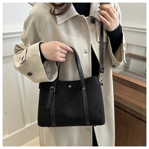 Detail of black suede tote bag with metal studs and layered pocket on soft shoulder straps
