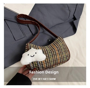 Detail of houndstooth shoulder bag with brown leather trim and plush cloud charm