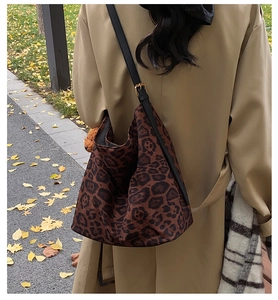 Detail of leopard print tote bag with black leather straps on a khaki trench coat