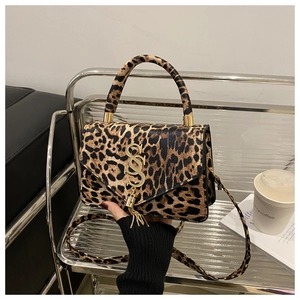 Détail du sac léopard avec logo SS doré, pompon et texture en cuir PU de qualité