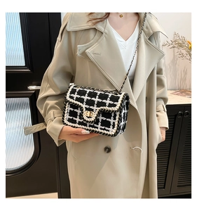Borsa a tracolla in tweed bianco e nero con chiusura dorata indossata su un trench beige