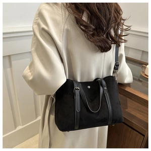 Close-up of black matte suede tote bag with leather straps and silver buckle detail