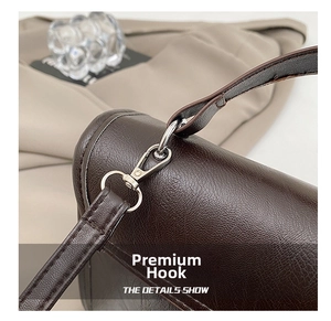 Macro detail of silver metal swivel hook on dark brown lychee texture leather bag