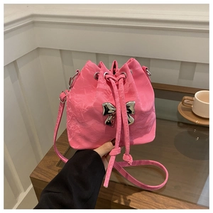 Detail of a pink drawstring bucket bag with a silver metal bow and pleated leather texture