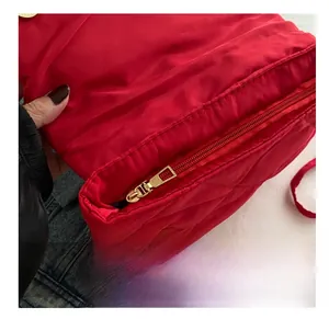 Détail du sac matelassé rouge avec fermeture éclair dorée et fermoir magnétique