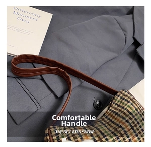 Detail showing the plaid tweed fabric texture and brown faux leather handle of the shoulder bag