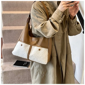 Detail of a brown leather tote bag with white fleece pocket and buttons on a khaki trench coat