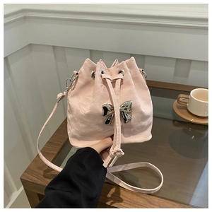 Detail of light pink drawstring bucket bag with silver metal bow and pleated texture
