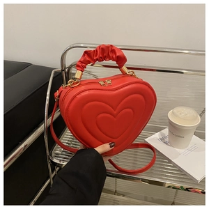 Detail of red heart-shaped bag with quilted texture and ruched handle on display