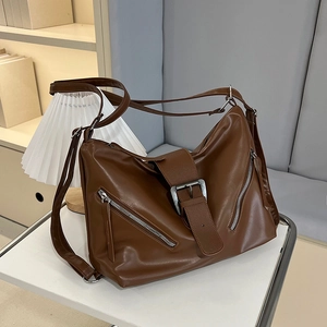 Brown vintage motorcycle style tote bag with dual zippers and buckles on a display stand