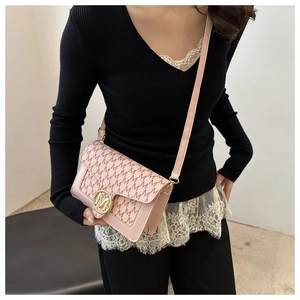 Détail du sac bandoulière rose clair avec motif monogramme et boucle dorée logo M