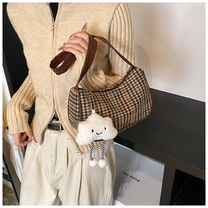 Close-up of vintage plaid underarm bag with leather strap and cute cloud plush charm
