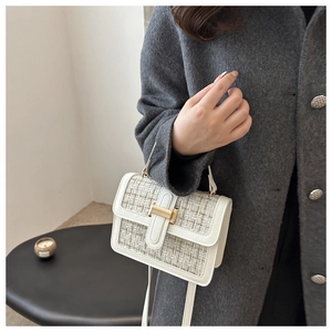 Detail of tweed crossbody bag featuring a golden H buckle on a grey wool coat background