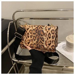 Detail of leopard print handbag with a wide black shoulder strap and gold hardware