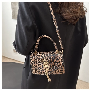 Sac bandoulière imprimé léopard porté sur une veste noire avec détail de pompon