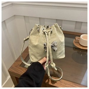 Detail of light green bucket bag with wrinkled texture and silver butterfly ornament