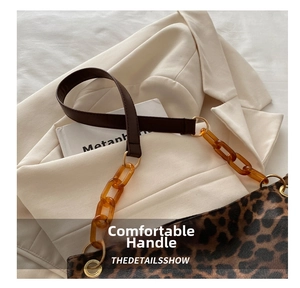 Close-up of leopard print tote featuring brown leather handle and amber acrylic chain detail
