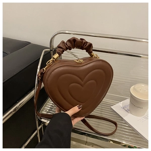 Detailed view of dark brown heart-shaped bag with ruched handle and embossed pattern