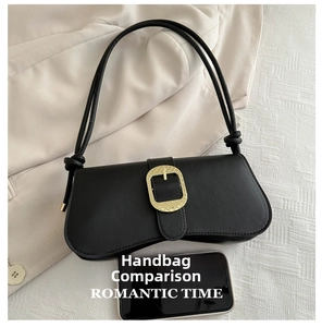 Matte black leather saddle bag with large gold buckle on beige blazer background