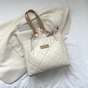 Quilted beige tote bag with chain strap and fashion label on elegant fabric background