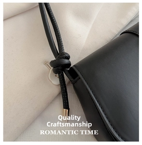 Detail of the knot craft on the shoulder strap of a black leather handbag with metal clasp