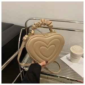 Close-up of heart-shaped handbag featuring quilted texture and ruched cloud handle