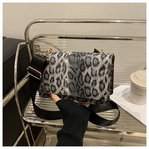 Detail of grey leopard print crossbody bag with black wide strap and golden hardware