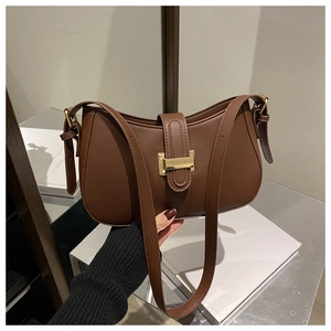 Close-up of brown faux leather shoulder bag with decorative gold rectangular buckle