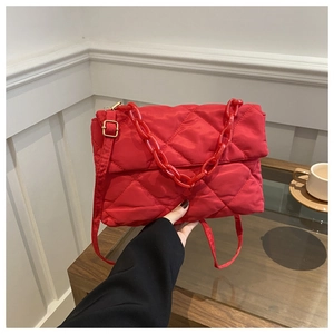 Close-up of red quilted nylon bag with chunky plastic chain and adjustable strap