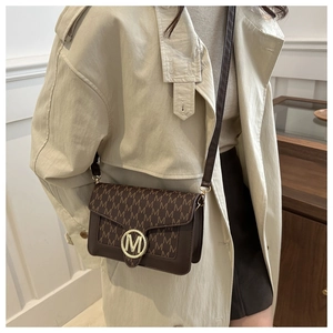 Détail du sac bandoulière marron rétro avec motif M et boucle dorée circulaire