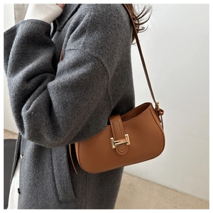 Caramel matte leather baguette bag with gold metal buckle detail shown on shoulder