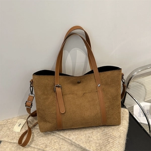 Brown vintage suede tote bag with leather straps and metal buckle shown in a lifestyle setting