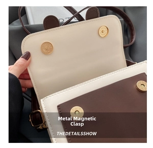 Detail of four golden magnetic buckles on a two-tone crossbody bag with bear ear design