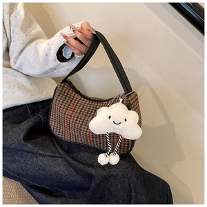 Detail of retro houndstooth bag with leather strap and cute white cloud charm accessory
