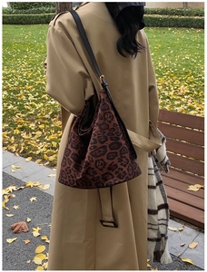 Detail of vintage leopard print tote bag with black leather straps on a khaki trench coat