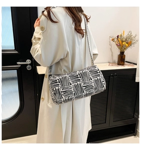 Side view of striped knit shoulder bag showing the stylish contrast pattern and wide strap