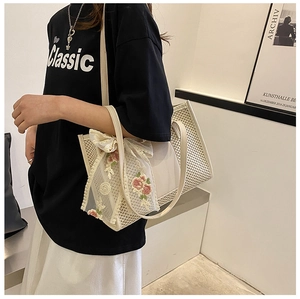 Close-up of cream woven tote bag with lace floral scarf and elegant leather handle detail
