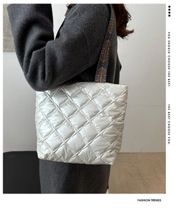 Detail of silver quilted tote bag featuring a colorful ethnic style woven shoulder strap