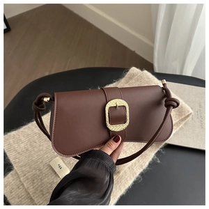 Detail of dark brown leather handbag with vintage gold buckle and knotted strap design