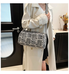 Modern cylinder shoulder bag with black and white geometric patterns and polka dot strap