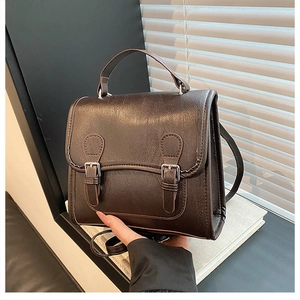 Detailed close-up of dark brown vintage PU leather bag with dual metal buckles