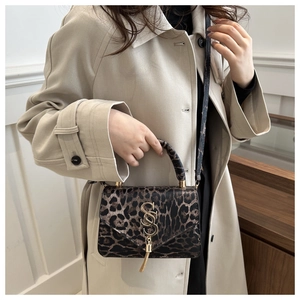 Détail du petit sac carré léopard avec logo en métal doré et pendentif à pompon