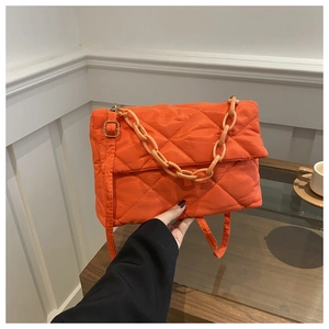 Close-up of orange quilted nylon handbag with chain handle and adjustable strap