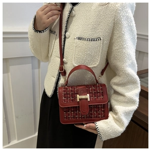Detail of red tweed flap bag with gold clasp and detachable shoulder strap on model