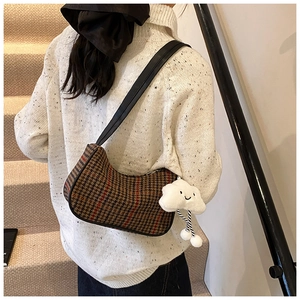 Houndstooth shoulder bag with leather strap and plush cloud charm on female model