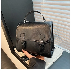 Close-up of black vintage leather backpack with dual buckle straps and textured finish