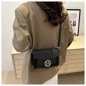 Détail d'un petit sac bandoulière noir avec motif M et boucle dorée sur un mannequin